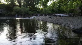 Low shot over small waterfall in Cumbria and shallow river in the sunshine