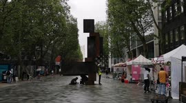 As the heavy rain pours in London after a heatwave people hide under a rather phallic looking sculpture to hide from the rain