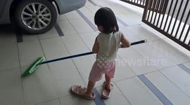 Funny toddler doing housework with mom's sandals
