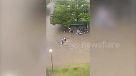 Schoolgirls push scooter stranded in flash flood amid sudden rain storm
