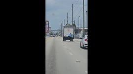 Man Hitches Ride On Back Of Truck