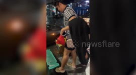 Stranded locals use bench to cross flood during storm