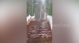 Rainwater cascades down temple stairs creating hypnotic ripples