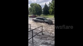 Cars drive through raging floods in Denver, US