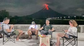 Chilled locals enjoy drinks as restive Mayon Volcano gently erupts in the background
