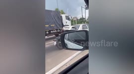 Sedan drives with motorcycle strapped onto open rear trunk