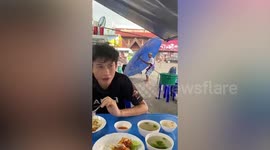 Street vendor struggles to close huge umbrella blown by storm