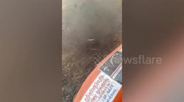 Terrifying dust devil tornado whirls toward farmer plowing field in Thailand