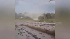 Landspout tornado spins across field during stormy weather in Thailand