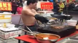 Shirtless man dances wildly while roasting squid