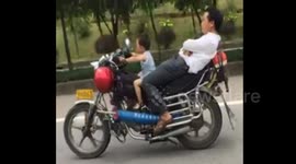 Four-year-old boy drives motorbike as dad reclines behind