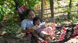A mother and baby relax in a hammock on a small farm in Northern Thailand.