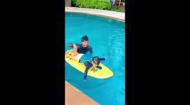 Father teaches toddler son to paddle on a surfboard for the first time