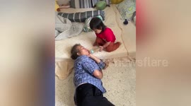 Cute toddler gives sleeping grandmother sips from her milk bottle