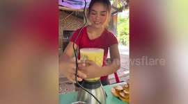 Street vendor spills mango juice all over blender when she tries to remove pitcher