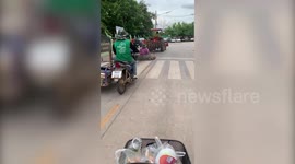 Farmer sits in large truck tire tied to the back of moving tractor