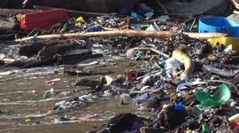 Heavy plastic pollution on a beach on a deserted island in Panama with waves crashing into the plastic trash moving it around in the ocean