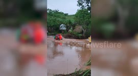 Good Samaritans help drivers carry motorcycles across flooded road