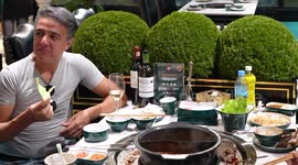 Hungry lion watches over people eat lavish sea food hot pots at restaurant in Cambodia