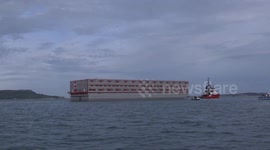Fiilmed at sea the Bibby Stockholm immigrants barge arrives at Portland today in Dorset after delays.