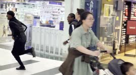 A Young Man Seen Riding E-Bike in Canary Wharf Shopping Mall, Followed By A Lively Crowd Running Behind