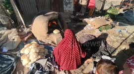 Palestinian woman prepares bread on a taboon oven in light of the high temperatures and the power outage in the Gaza Strip.