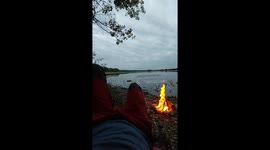 Man enjoying a bonfire near the lake in the dusk, ultimate relaxation video.
