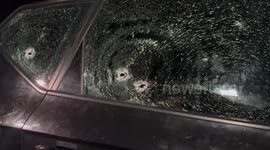 Palestinians stand next to a bullet-ridden car in which a Palestinian was killed late by Israeli forces, in an incident described by the army as a