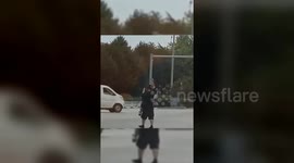 Driver carries elderly woman across street amid busy traffic