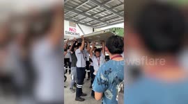 Short apprentice struggles to reach plane wing being carried by his colleagues