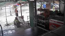 Frantic shopkeeper holds down umbrella during storm in Thailand