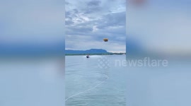 Thrillseeker rides flying inflatable pulled by jet ski on lake in Thailand