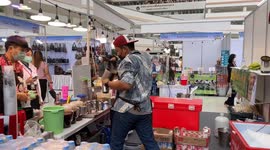 Tea seller twirls while pouring drink at trade fair in Thailand