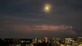 Full moon and lighting bolts emerge through cloudy sky above Washington DC