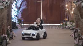 Toddler chosen as ring bearer falls asleep while riding toy car down the aisle (with alternative angle)