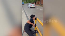 Event worker trips into metal barrier while chasing chair blown by wind