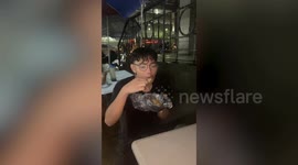 Diner carries on eating meal while being battered by heavy rain during flood