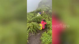 Hikers caught in storm crouch on hillside while being battered by wind