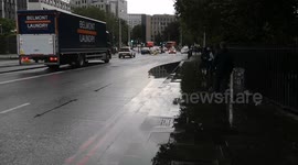 A tourist gets soaked as a car drives through a big puddle on the road caused by the heavy rain that hit London. Footage was filmed right by the Tower of London