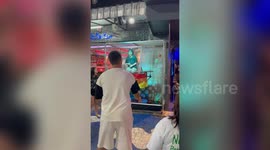 Tourists play game throwing balls at cage to dunk a girl in cold water