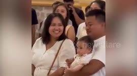Cute baby can't stop giggling as priest speaks during baptism mass