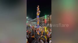 Festival daredevils drop kid attached by rope from 30ft high bamboo pole