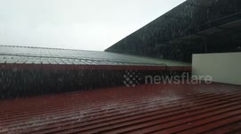 Heavy rainfall with water falling on the roof and overflowing onto the roads.