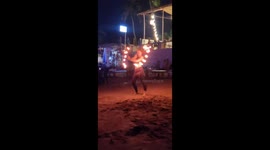 Experience the allure of Goa's shoreline as a skilled girl mesmerizes a growing crowd with her graceful fire play, creating a harmonious dance of flames against the tranquil beach backdrop in this captivating 12-second video.