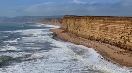 Rough seas from Storm Betty crash ashore on the beach at Burton Bradstock in Dorset on a hot sunny afternoon.