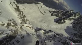 Speedrider skier rides an avalanche off a cliff