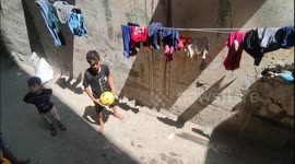 Palestinian children play football outside their home in the Shati refugee camp