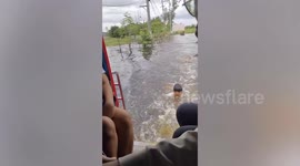 Kids surf on the back of bus pulling them through flood