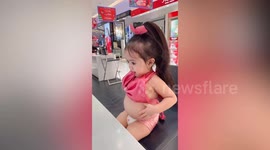 Adorable toddler plays with her tummy in front of mirror