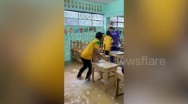 Schoolboys catch fish in flooded classroom during break time